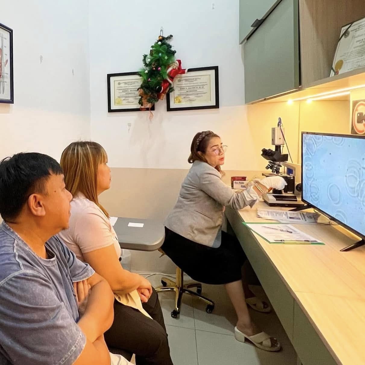 Practitioner showing live blood analysis results to two patients